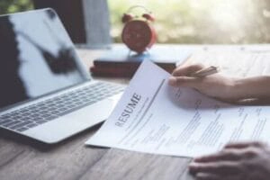 istockphoto-1149054436 Job seeker review resume application on desk, laptop computer and prepares for modern resume writing and coaching.